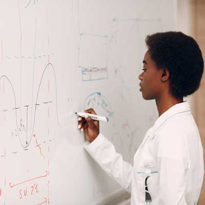 a student writing out math problems on a whiteboard